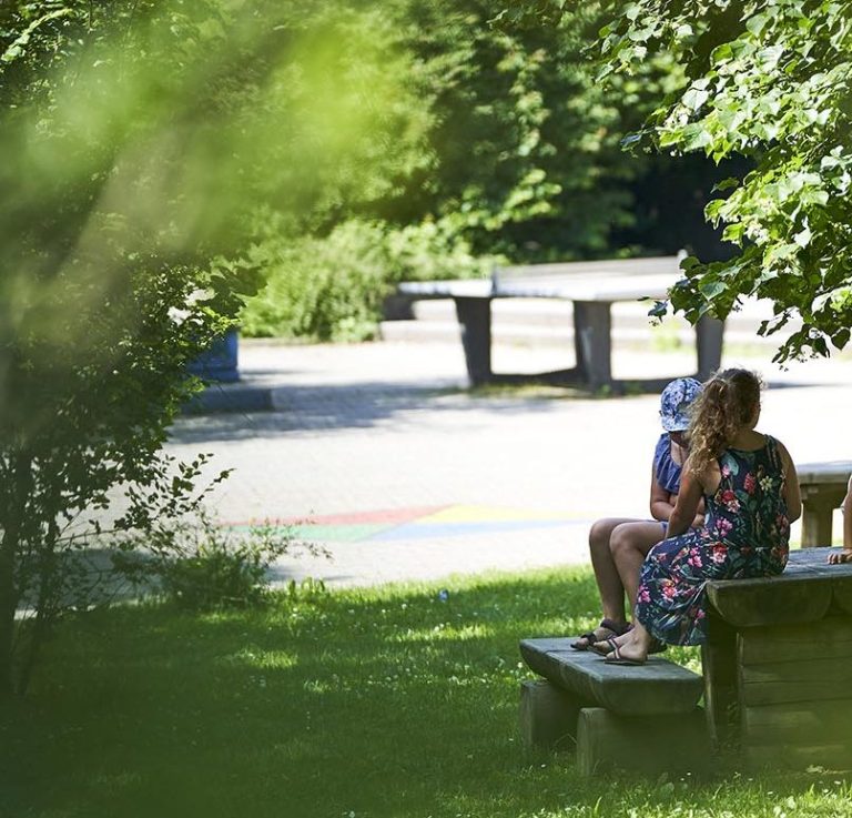 Kinder sitzen an einem Tisch auf dem Schulhof